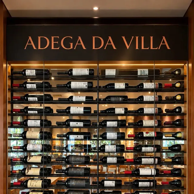 Cava de la Adega da Villa, con botellas de vino acostadas en un expositor de vidrio iluminado