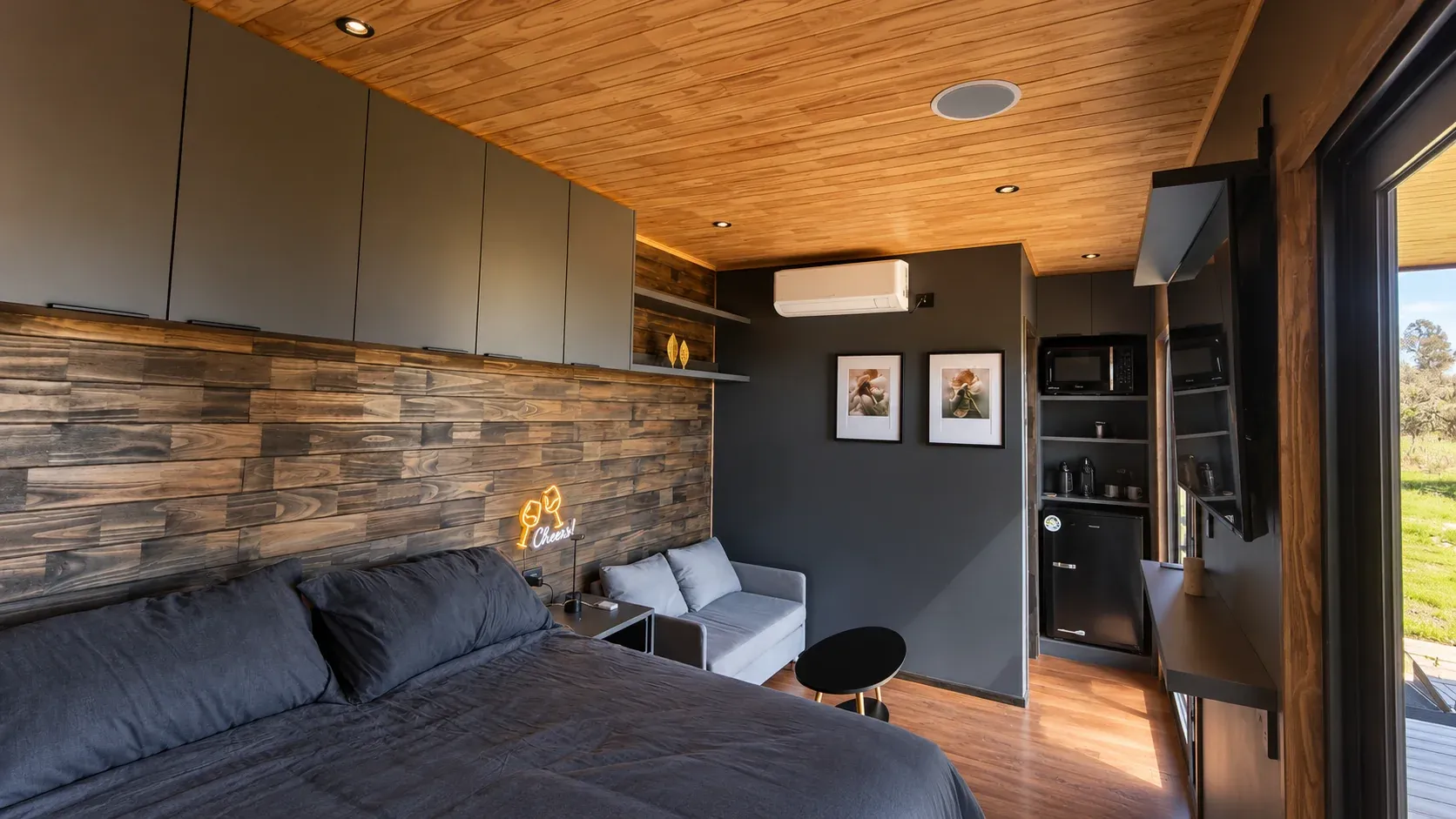 Interior del Rhenus Wine Lodge: la cama, el sofá y la cocina, con muro de madera y techo claro